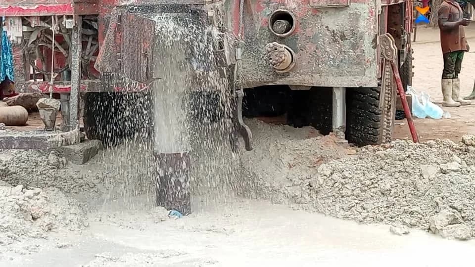 آلة الحفر أثناء العمل، والماء والطين يندفعان من البئر